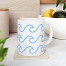 White ceramic mug with wave pattern in light blue on a coaster on kitchen counter