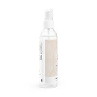 Clear spray bottle of natural face toner for hydration with white pump and subtle label design