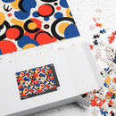 Printify colorful eco puzzle with abstract circular patterns partially assembled next to its open white box