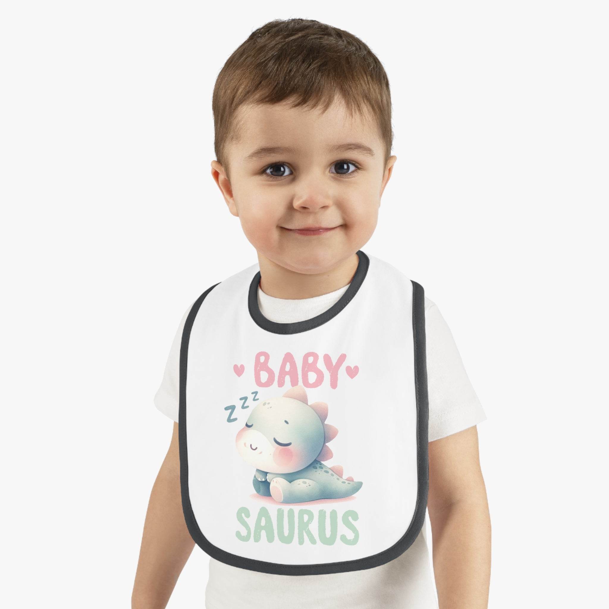 Smiling toddler wearing a dinosaur print baby bib with sleeping baby dinosaur design