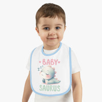 Toddler wearing a dinosaur print baby bib with a cute sleeping dinosaur design and blue trim