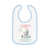 White dinosaur print baby bib with blue trim featuring a sleeping baby dinosaur and text baby saurus