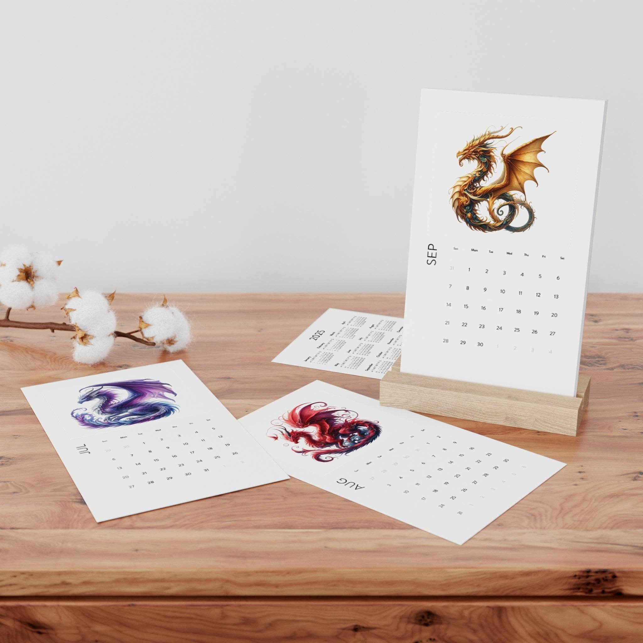 Printify eco-friendly 2025 desk calendar with dragon artwork on wooden stand and loose calendar pages on wood surface
