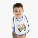 Toddler wearing a Printify eco-friendly baby bib with blue trim and cute jungle animal design