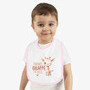 Toddler wearing Printify eco-friendly baby bib with pink trim and cute giraffe design