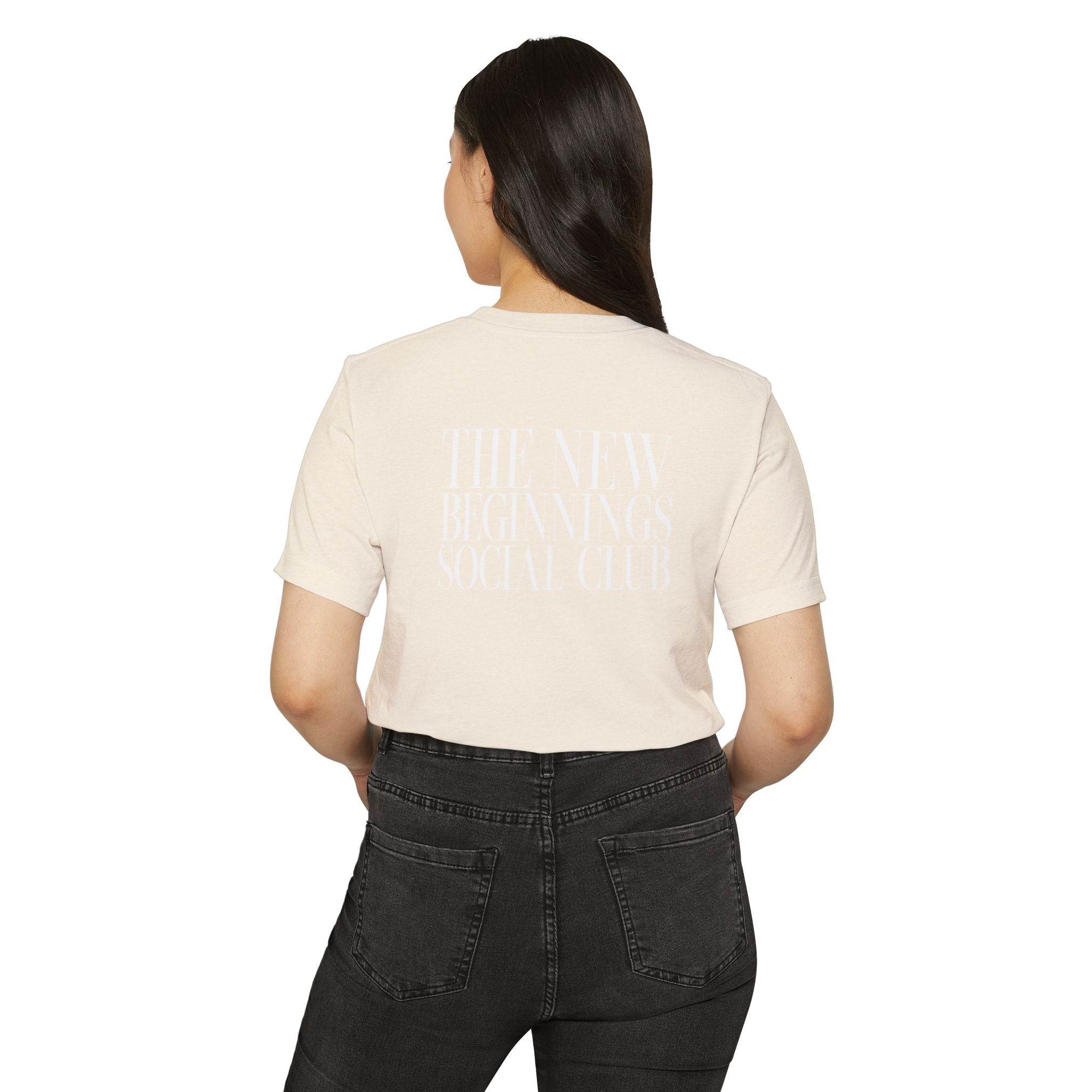 Printify eco-friendly fashion tee in beige with back text worn by woman with black jeans