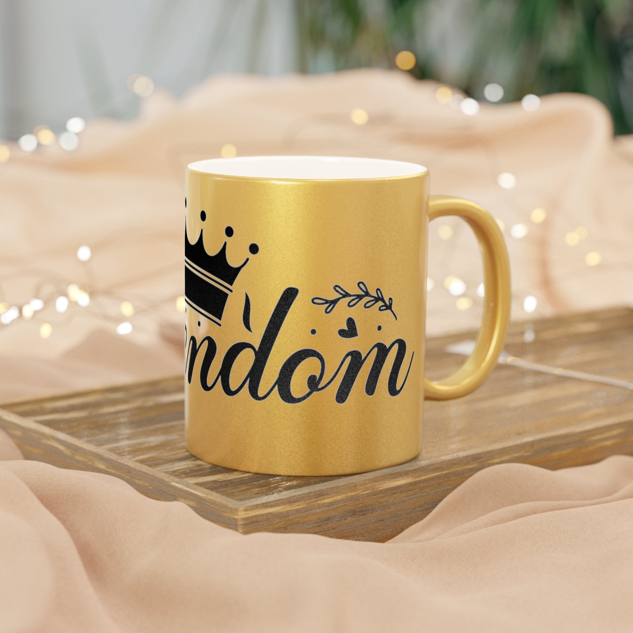 Gold eco-friendly metallic mug by Printify with black crown and random text on wooden tray
