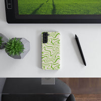 Printify eco-friendly phone case with green abstract wavy design placed on white desk next to plant and pen