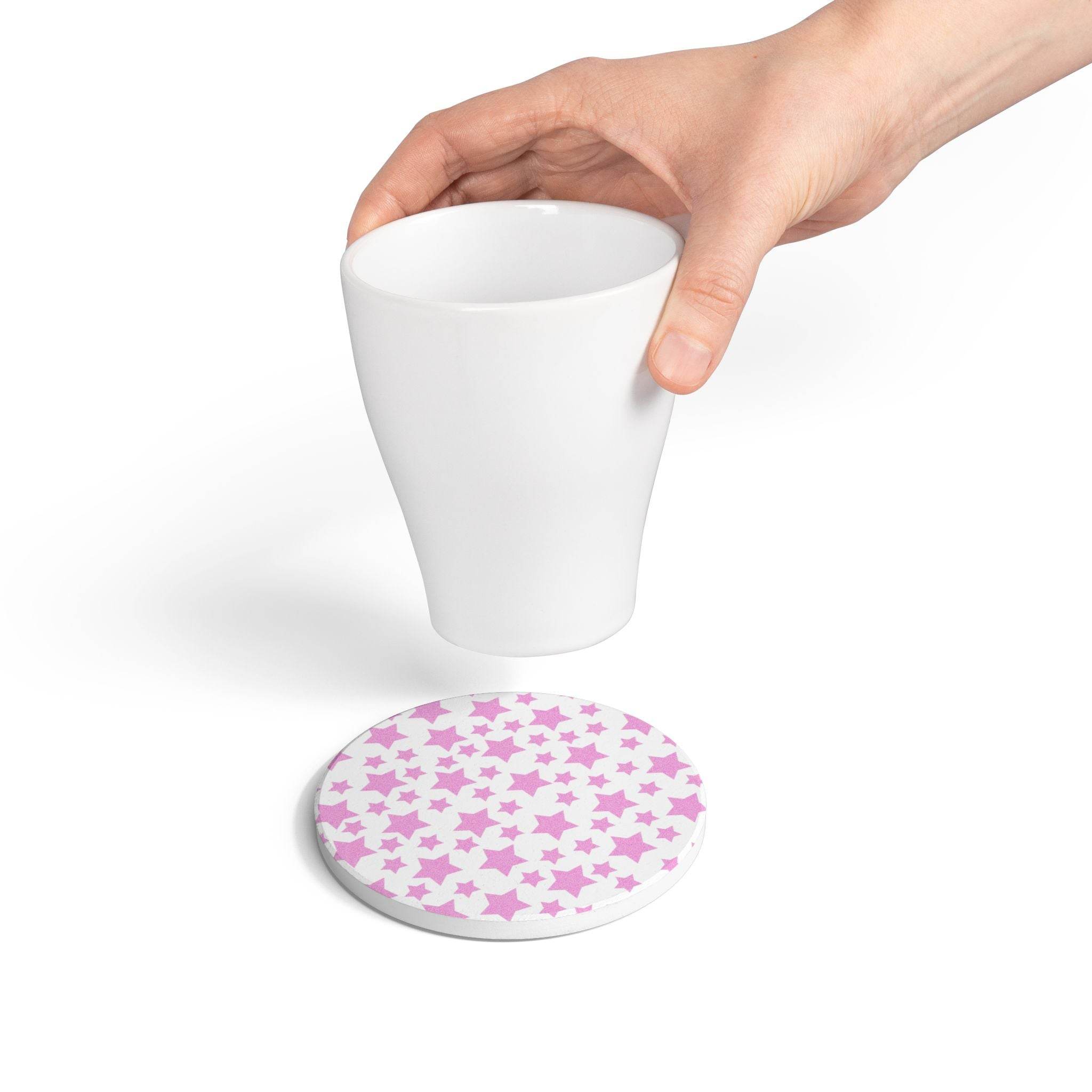 Hand holding white cup above eco-friendly pink ceramic coaster with star pattern from Printify