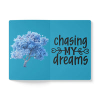 Open eco-friendly softcover journal by Printify with blue tree illustration and chasing my dreams text