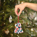 Hand holding eco-friendly wooden ornaments shaped like a bell with colorful leaf patterns in front of a Christmas tree