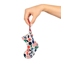Hand holding colorful eco-friendly wooden ornaments shaped like a Christmas stocking with a red string