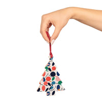 Hand holding eco-friendly wooden ornaments shaped like a Christmas tree with colorful abstract design