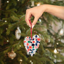 Hand holding eco-friendly wooden ornaments heart shaped with colorful leaf design near decorated Christmas tree