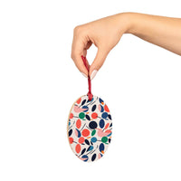 Hand holding colorful eco-friendly wooden ornaments with red ribbon for seasonal decorations