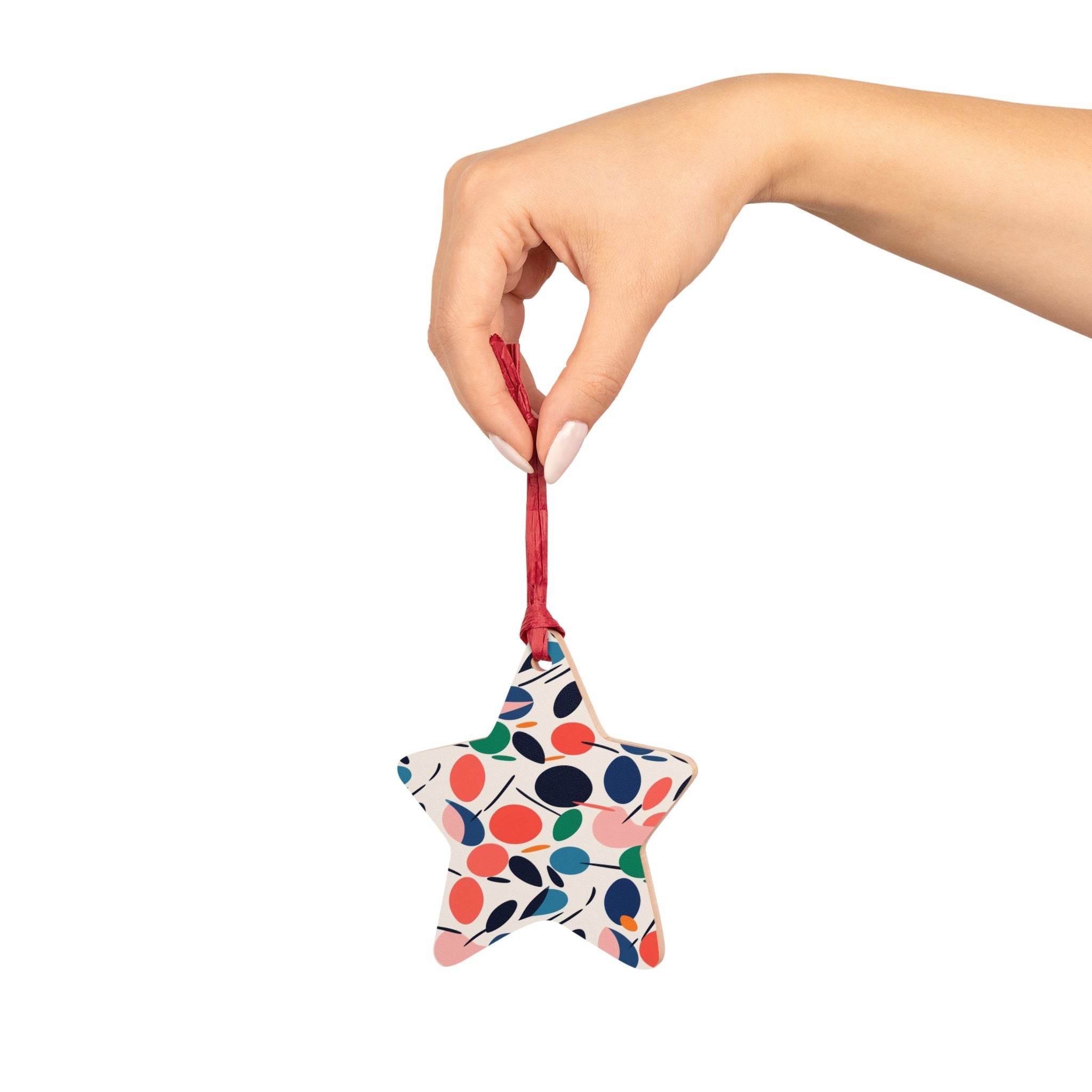 Hand holding a colorful star-shaped eco-friendly wooden ornament with red ribbon for seasonal decorations