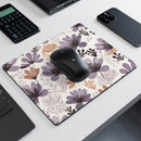 Floral rectangular mouse pad with purple and beige flowers and a black wireless mouse on a white desk