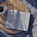 Open book with eco-friendly art bookmark featuring colorful abstract design on wooden table with glasses and coffee cup