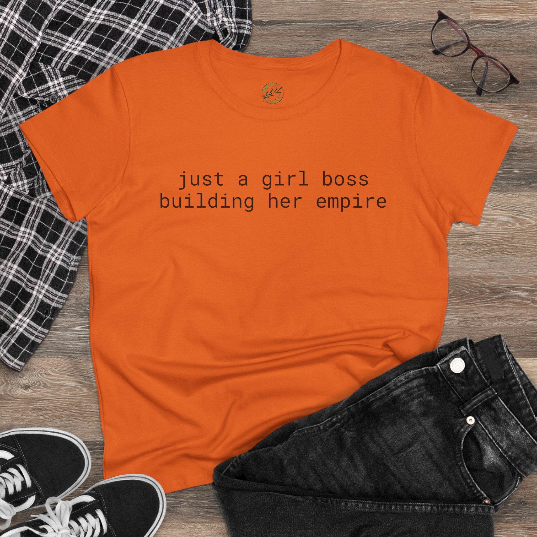 Orange t shirt reading just a girl boss building her empire flatlay with jeans sneakers glasses eco-friendly girl boss shirt