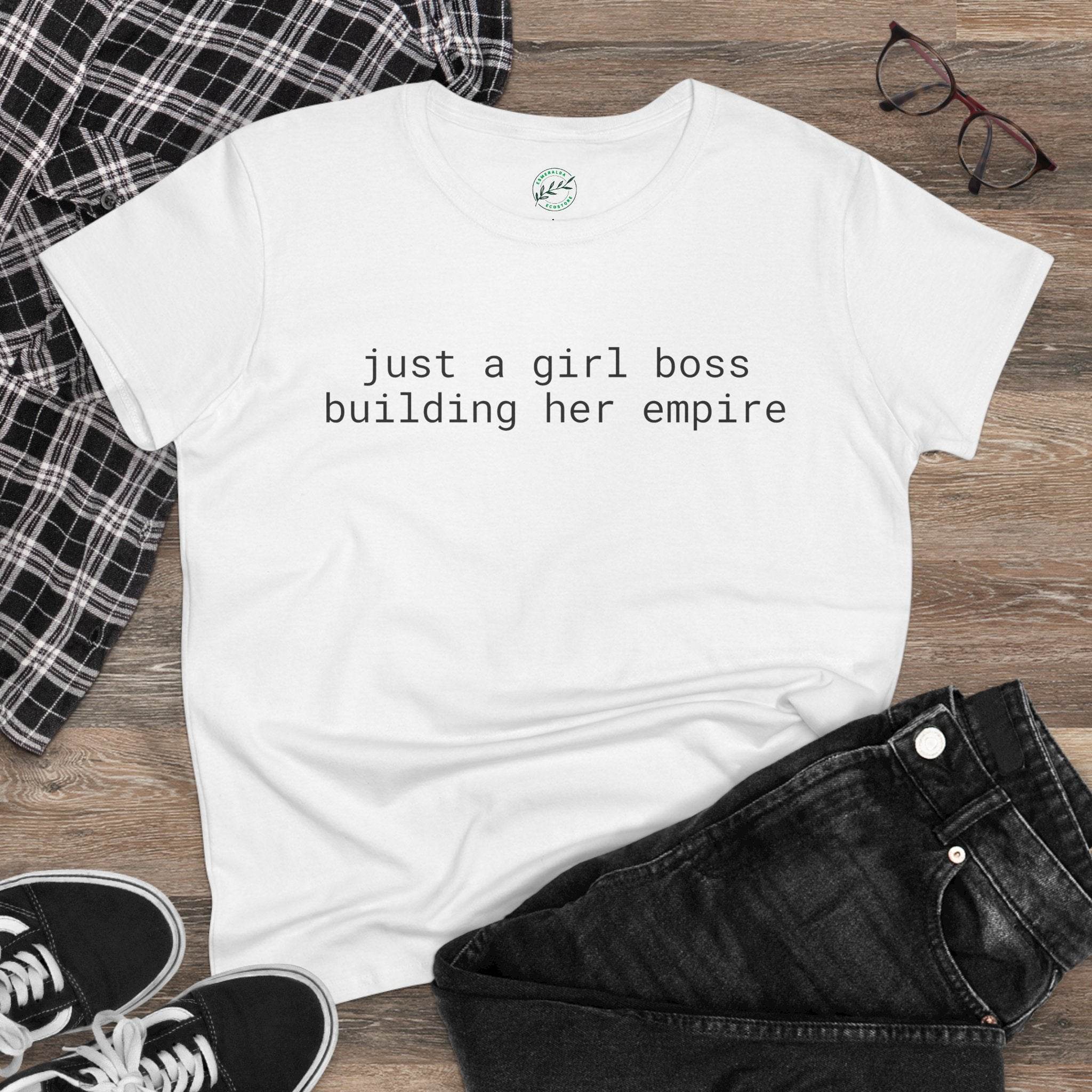 eco-friendly girl boss shirt white tee reading just a girl boss building her empire flat lay with black jeans sneakers and glasses