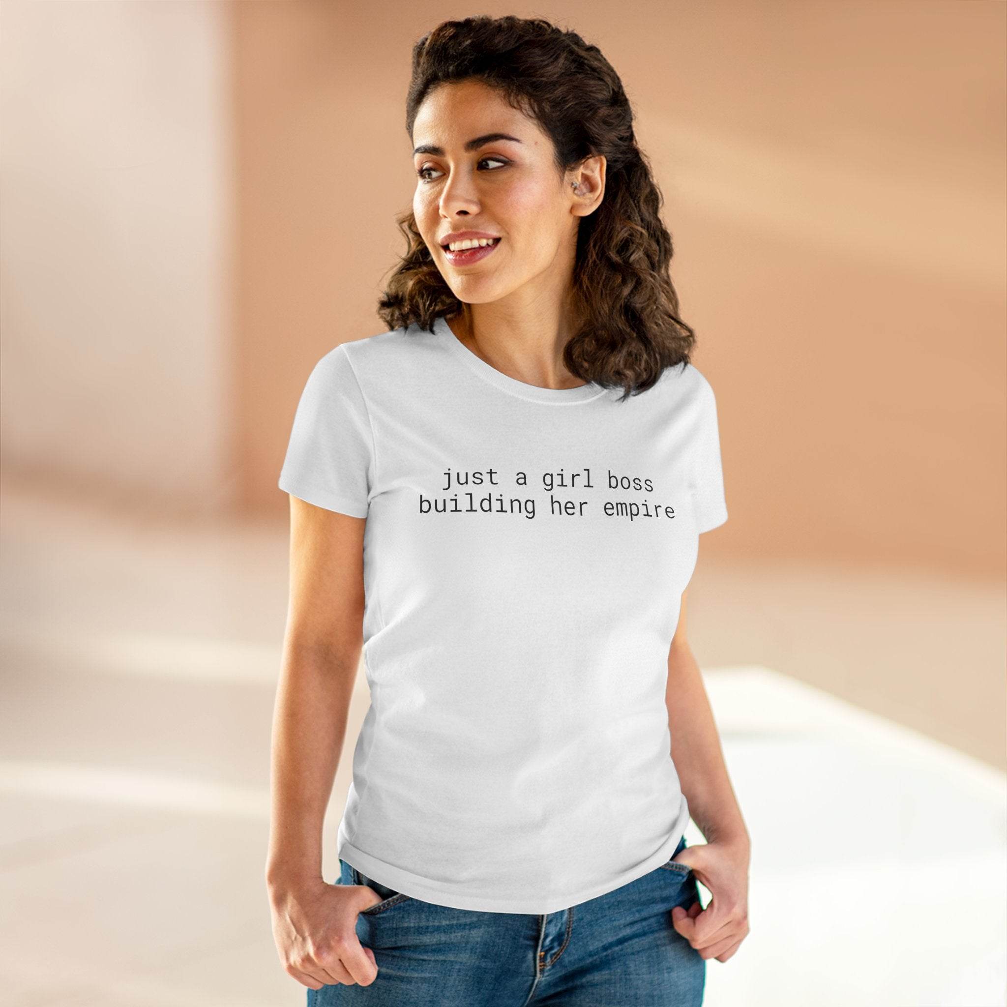 Smiling woman in jeans wearing a white fitted Printify eco-friendly girl boss shirt with slogan