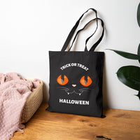Black eco-friendly Halloween tote bag by Printify with orange cat eyes and trick or treat text