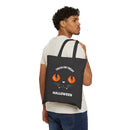 Man carrying Printify black eco-friendly Halloween tote bag with orange cat eyes and trick or treat text