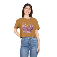 Woman wearing a brown Petal & Crown eco crop shirt with a pink crown design paired with blue jeans