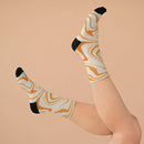 Printify recycled poly socks with orange and cream swirl pattern and black heel and toe on raised feet