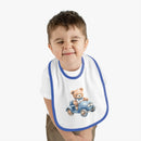 Toddler wearing a Printify sustainable baby bib with a blue trim and teddy bear driving a car design