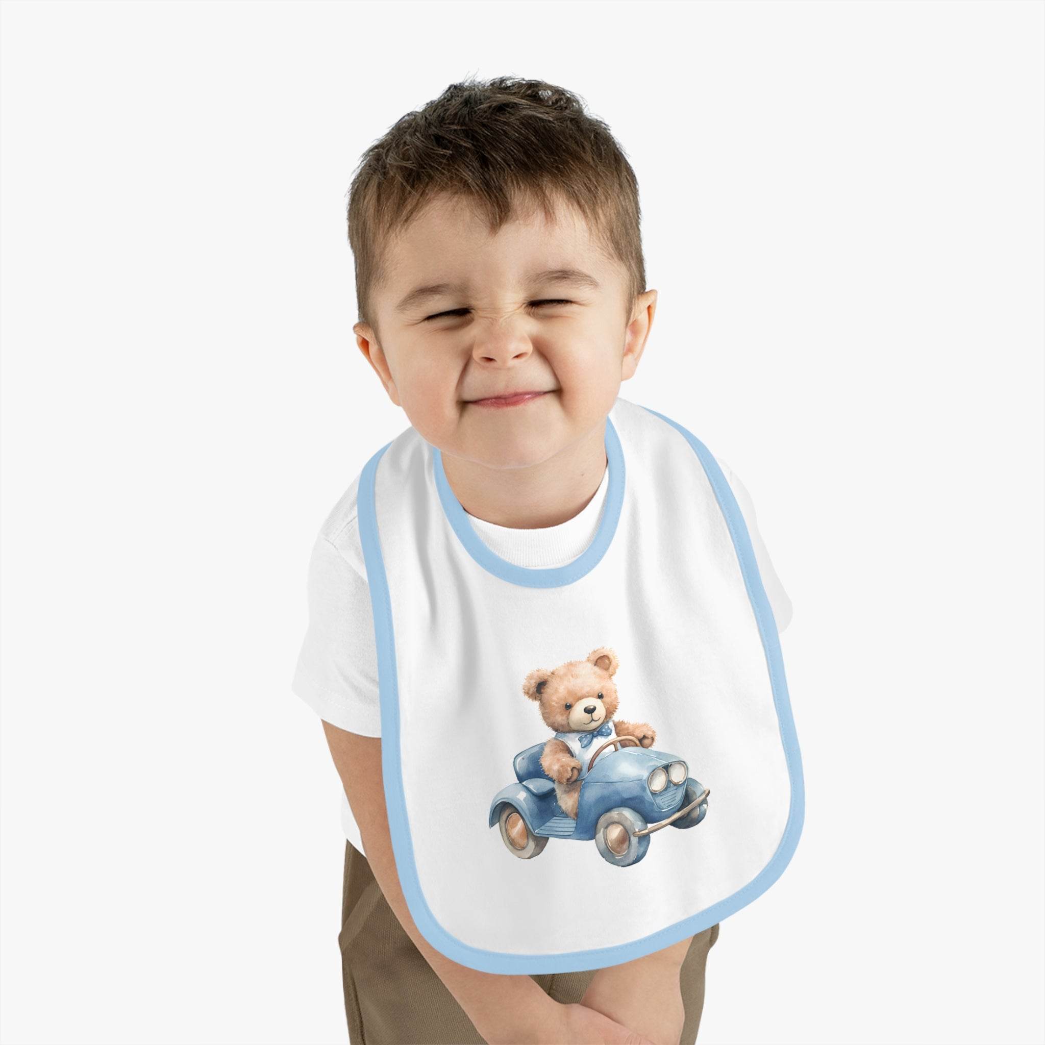 Toddler wearing Printify sustainable baby bib with blue trim and teddy bear driving a car design