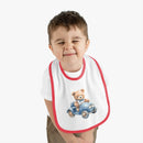 Toddler wearing a sustainable baby bib with red trim and teddy bear driving a blue car design
