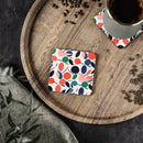 Colorful sustainable drink coasters with abstract leaf pattern on wooden tray holding coffee cup