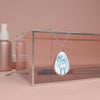 Printify sustainable oval necklace with deer design on silver chain displayed on glass box