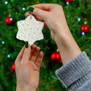 Hands holding a twinkling stars holiday decoration shaped like a snowflake in front of a decorated Christmas tree