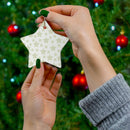 Hands holding a twinkling stars holiday decoration star ornament in front of a decorated Christmas tree