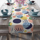 Printify eco-friendly table runner with colorful abstract floral design on wooden dining table