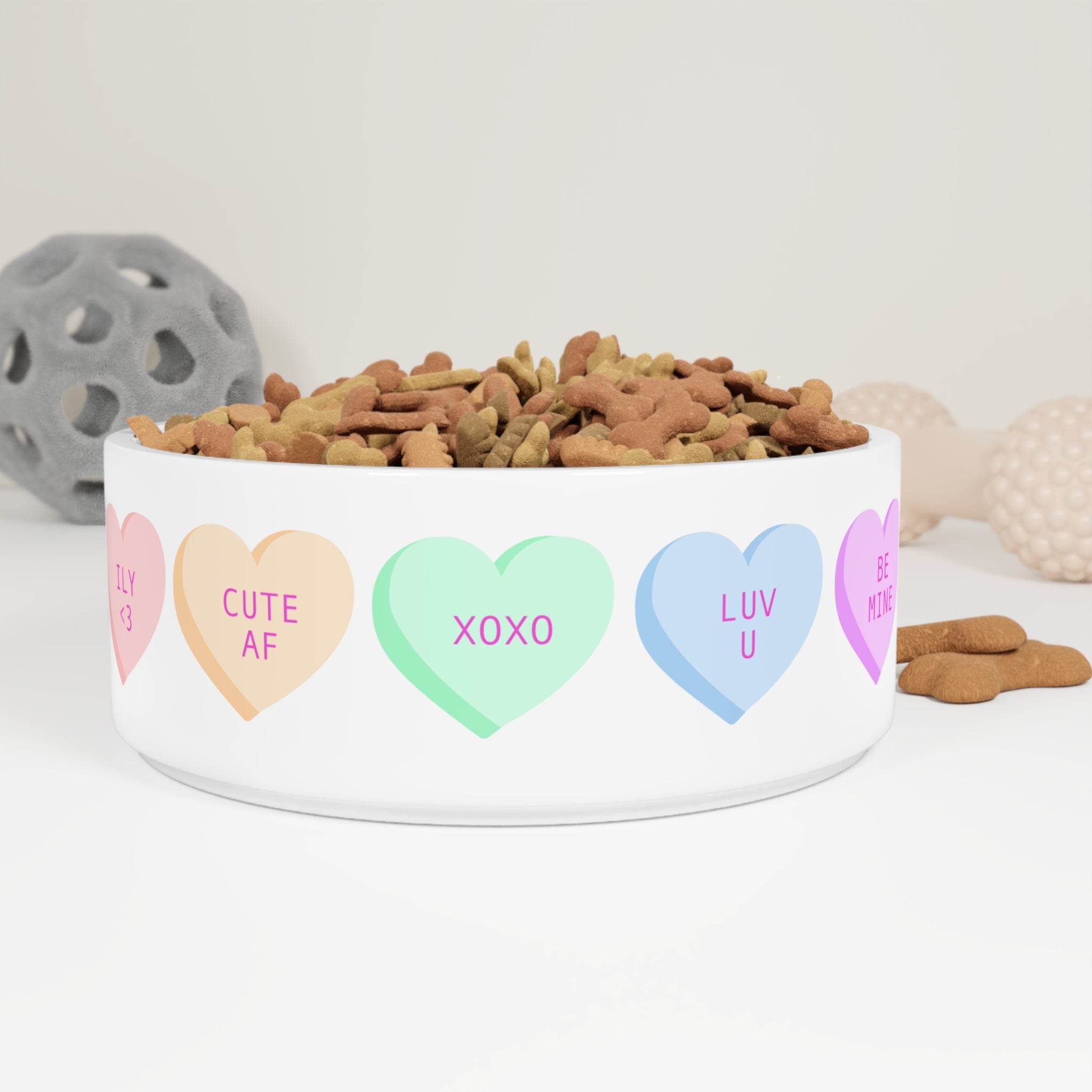 White pet bowl with colorful hearts featuring XOXO design pet bowl filled with dog treats