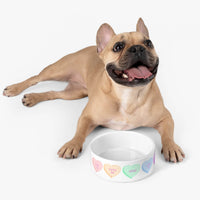 Happy dog lying next to a white XOXO design pet bowl with colorful heart patterns